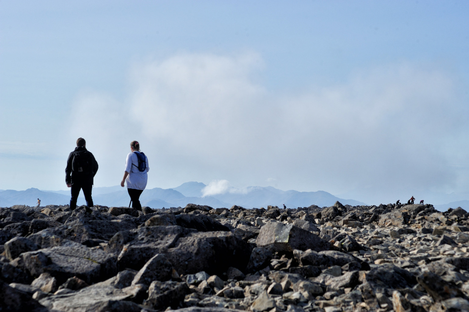 Two people standing in the rocky landscape of the summit of Ben Nevis, Scotland.
